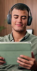 Headphones, tablet and man on home sofa for streaming, podcast or browsing online to relax. Male person, technology and audio subscription in house for happiness, internet and listen to sound