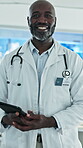 Face, healthcare and tablet with black man doctor in hospital for development, planning or research. App, medical and smile with mature African surgeon in clinic for insurance, records and wellness