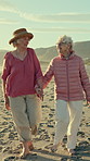 Beach, old women and holding hands on walk on holiday, retirement and happy for reunion on adventure. Outdoor, friends and elderly people on summer vacation, bonding and travel together on getaway