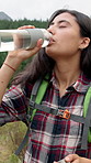 Woman, drinking and water with bottle for hiking break, recovery or hydration in nature. Female person, mineral and liquid with refreshing beverage for rest or natural sustainability on trekking path