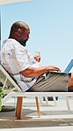 Outdoor, champagne and businessman with laptop on holiday, digital nomad and typing story on website. Drinking, alcohol and black person with tech on vacation, remote work or mature author with drink