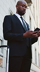 Waiting, phone and business black man in city with luggage for transport, lift service and taxi. Low angle, lawyer and person with suitcase on cellphone for travel, commute and order cab in town