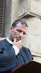 Judge, man and folder with thinking in city for court case, review and notes with legal career. Mature person, magistrate and low angle with documents, legislation or justice with insight for report