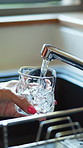 Hands, faucet and glass for water at kitchen sink for hydration, detox and beverage in morning. Person, tap and basin for drink, thirsty or electrolytes for wellness with digestion at apartment