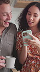 Coffee, talking and couple with phone in kitchen for online news, conversation and bonding in morning. Happy, home and man with woman on cellphone for social media, internet post and laugh for joke