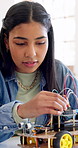 Robotics, classroom and girl in school for learning, discussion or future development. Student, wiring and education with electronics, transportation or machine for knowledge or engineering project