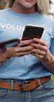 People, volunteer and hands with phone in park for social media post, network or outreach. Activist, charity group or NGO team typing with smartphone for sharing app, data sync or community service