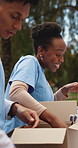 Box, packing and volunteer group outdoor together for charity, community or donation collection. NGO, package and service with activist people in park for collaboration, outreach project and support