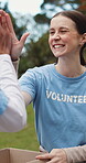 Box, high five and volunteer team outdoor together for charity, community or donation success. Motivation, NGO and packing with activist people in park for collaboration, outreach goals and support