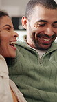 Couple, laughing and hug on break in lounge, bonding and romance with partner on couch or affection. Happy man, love and embrace with woman on sofa, home and relax with smile on weekend and cuddle