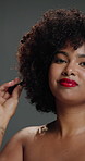 Face, woman and comb with haircare in studio with curly texture, natural growth and maintenance. Portrait, person and brush with coil hair for styling treatment, grooming benefits and gray background