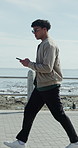 Ocean, walking and typing with man, phone for online chatting and map for directions. Seaside, mobile user and person with tech for social media, destination and connection for communication in Miami