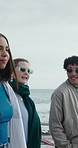 People, friends and chat on promenade at beach with smile, walk and bonding on seaside vacation. Women, men and gen z group on holiday for discussion, memory or tourism with break on getaway by ocean