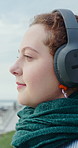 Outdoor, calm and woman by beach with headphones for online meditation, podcast or music for peace. Relax, breathing and female person with audio tech for listening to playlist or album on promenade.