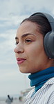 Woman, mindfulness and headphones for music at beach, relax and listening to entertainment on break. Outdoor, tourist and happy person with tech for audio, breathe or streaming song on winter holiday