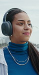 Headphones, outdoor and woman by beach for holiday with listening to music, playlist or radio. Happy, audio tech and person on promenade by ocean for streaming album on vacation or weekend trip.