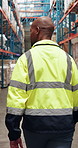 Black man, logistics and inspection with inventory in warehouse for quality assurance or security. Back view, male person or supplier walking in aisle for distribution, freight safety or storage