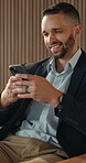 Phone, smile and text message with business man in office for break, communication or response. App, social media and typing with happy employee in workplace lobby for mobile or online chatting