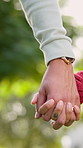 Holding hands, nature and couple on date with love, bonding and care outdoor together with loyalty. Marriage, commitment and man with woman for connection or trust in relationship on anniversary.