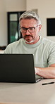Research, glasses and man with laptop in home, creative and editing novel on website and remote work. Author, online and mature person with technology for ebook, typing and story development in house
