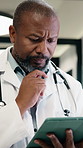 Doctor, man and reading in hospital with tablet, medical research and problem solving for test results. Mature, black person and healthcare worker thinking with tech, review diagnosis and planning.