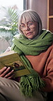 Reading, glasses and old woman with book in living room, learn and skill development with knowledge. Happy, senior person and comfortable on weekend with non fiction, hobby and retirement in house