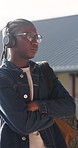 Student, man and outdoor at college with headphones, streaming music or education for development. Black person, relax and audio tech on university campus with radio, playlist or learning for growth.