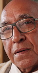 Face, glasses and happy with senior man in home living room for contemplation or retirement. Eyewear, relax and thinking with old person in apartment for reflection, nostalgia or weekend wellness