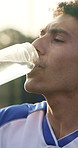 Thirsty, man and soccer player drinking water with break for practice, fitness and sports hydration. Athlete, person or footballer outdoor with bottle, electrolytes or refreshing liquid for wellness.