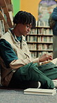 Man, student and reading in library with textbook for learning, education or study material. Person, academic scholar or learner with books, novel and thinking for literature research at university