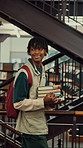 Man, student and walking with books in library for education, knowledge or learning in university. Male person, academic or learner with smile, textbooks or aisle for studying material or information