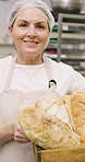 Crate, face and rolls with baker woman in commercial kitchen for cooking satisfaction. Box, carrying and pastry with mature person in bakery or restaurant for professional pride as happy chef