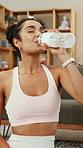 Fitness, woman and drinking water in home with bottle, exercise break and healthy habits for wellness. Thirsty, female person and beverage in lounge with hydration, electrolytes and workout recovery.