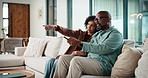 Couple, watching tv and remote on sofa with smile, choice and point with show in living room. Mature man, woman and decision with movies, television or film subscription on couch in lounge at house