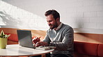 Creative, remote work and businessman with laptop in cafe, typing or email marketing on social media. Happy, freelancer and person with tech for article publication, research and blog post in shop
