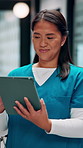 Reading, nurse and asian woman with tablet in hospital, medical journal and healthcare publication. Review, smile or person with newsletter for clinical treatment policy, tech or typing for research