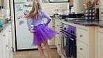 Kid, home and dance with energy, jump and creative performance with dress for music in kitchen. Girl, child and moving to audio at house with talent for rhythm, tutu and weekend celebration from back