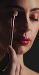 Makeup, eyeshadow or woman with brush in studio, apply powder or glamour aesthetic for glowing skin. Beauty product, facial routine and person with cosmetics for shine, tools and dark background