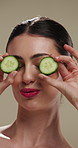 Face, woman and skincare with cucumber for beauty, vitamin c or brighten skin in studio background. Portrait, person or fruit for organic cosmetics, facial hydration and cooling benefits for wellness