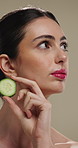 Thinking, woman and skincare with cucumber for beauty, vitamin c or brighten skin in studio background. Vision, person and fruit for organic cosmetics, facial hydration and cooling benefits for shine