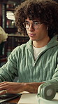 Student, typing and earphones in library with laptop, streaming music or essay for college education. Man, research and audio tech in university with computer, song or learning for english assignment