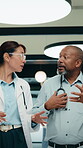 Doctors, walking and talking in hospital corridor for medical strategy, treatment or urgent care. Physician, woman and colleague in healthcare service, discussion or patient problem solving in clinic