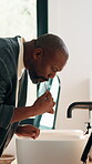 Man, brushing teeth and dental care with toothbrush in bathroom, home or wash mouth for fresh breath. House, sink and mature black person with toothpaste for oral hygiene, cleaning and wellness