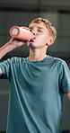 Tennis, boy or child drinking water on court with break, development or hydration for sports practice. Teen kid, training recovery and bottle at padel club with refreshing liquid, wellness or fitness