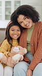 Smile, face and mom with daughter on sofa for comfort, bonding and trust in home. Teddy bear, love and portrait with woman and girl or child for relationship, affection and connection on weekend