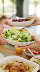 Food, hands and family with lunch in home for nutrition, wellness or health meal for celebration. Party, salad and group of people eating in dining room for serving vegetables at dinner in house.