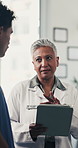 Doctor, woman and tablet with team at meeting in hospital for talk, review or insight for wellness. People, tech and discussion for planning, feedback report or app for healthcare services at clinic