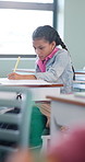 Learning, child and writing test in classroom, development and knowledge with book at school. Notes, girl and student in lesson for education, assignment info or studying for exam with assessment