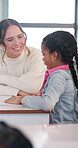 Teacher, help and girl in classroom with conversation, knowledge or question for school test. Education, support and student with woman at desk for learning, explaining or guidance in development