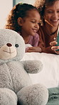 Mom, girl and teddy with tablet on bed for bonding, development or puzzle in home. People, mother and daughter with tech, education or online course on application with toy bear at family house